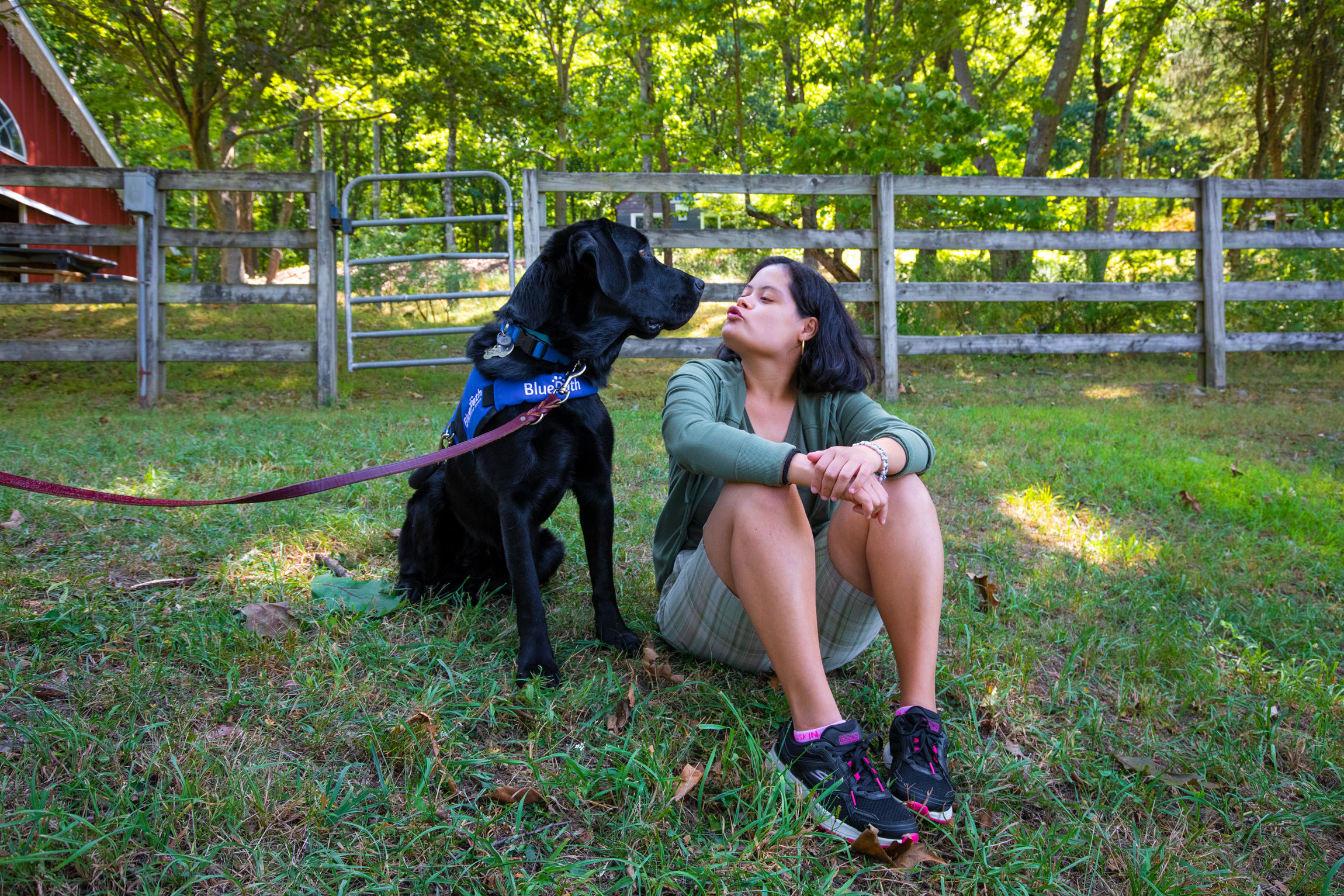 BluePath autism service dog sits with woman on the farm.