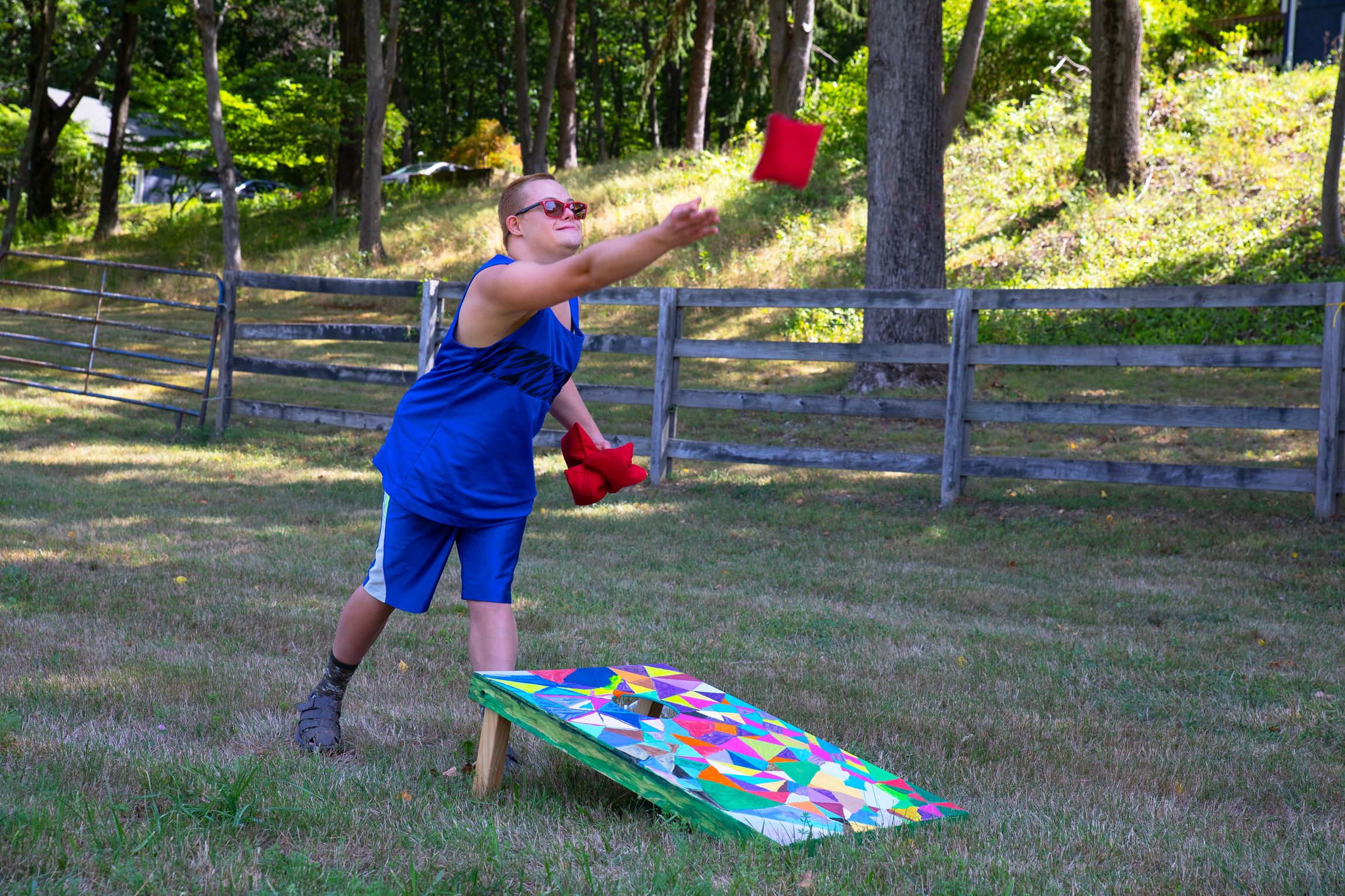 This young man tosses bean bags during outdoor activity time on the farm.