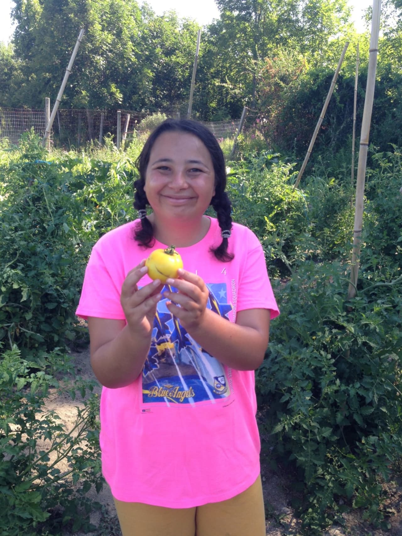 Girl holding tomato she helped grow with agriculturally based vocational training